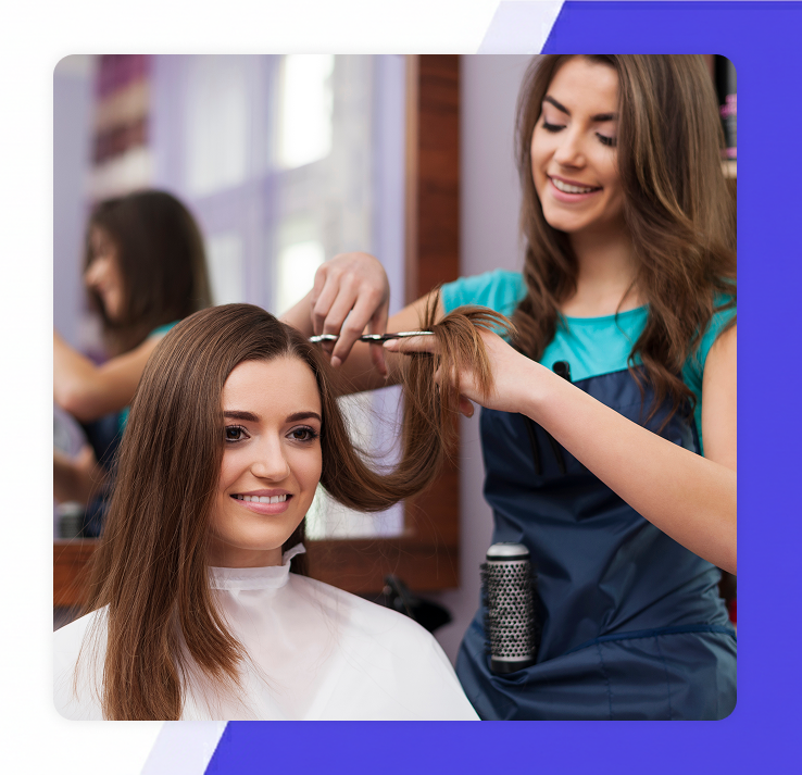 smiling female stylist trimming a woman's long brown hair in a bright hair salon
