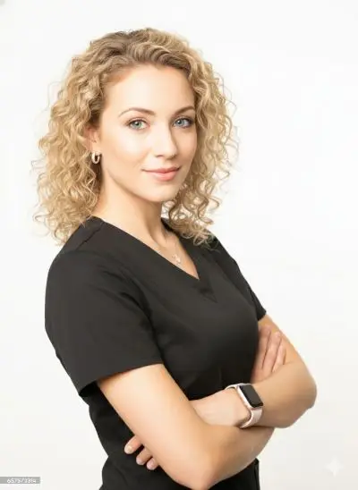 woman with blonde curly hair in black scrubs with crossed arms, wearing a smartwatch on a white background